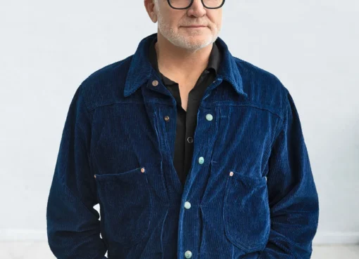 Bradley Whitford smiling on a Broadway stage under a warm spotlight.