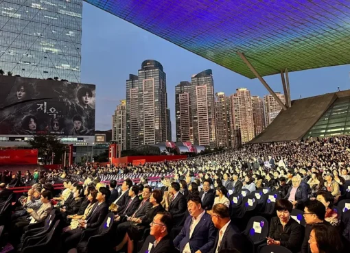 An artistic photo showing the vibrant energy of the Busan International Film Festival, perhaps a shot of an audience or a stage.