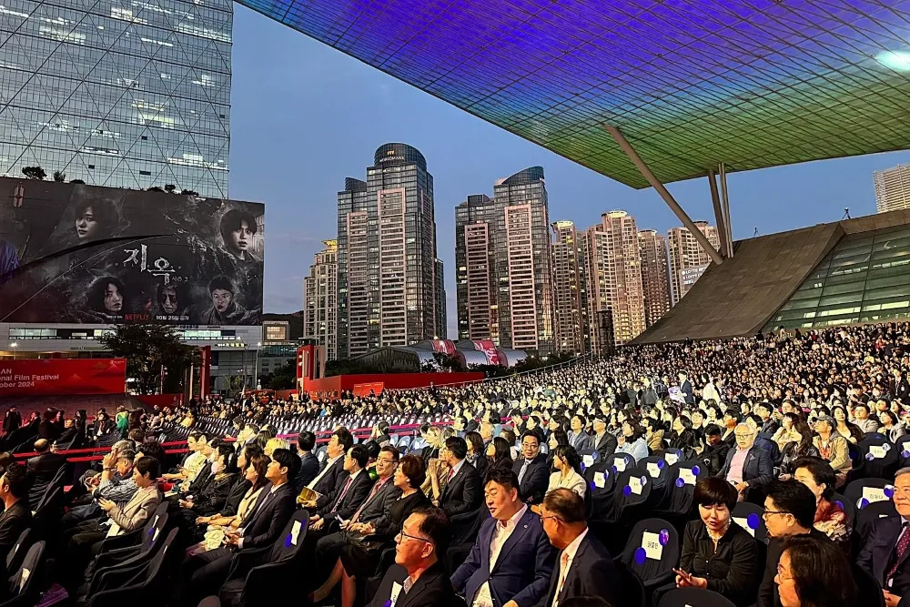 An artistic photo showing the vibrant energy of the Busan International Film Festival, perhaps a shot of an audience or a stage.