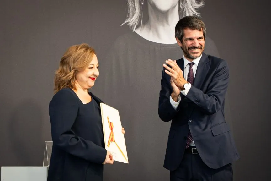 Carmen Machi smiling brightly while holding a prestigious award at a film festival.