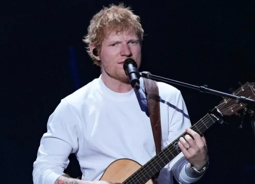 Ed Sheeran performing on stage with a guitar.