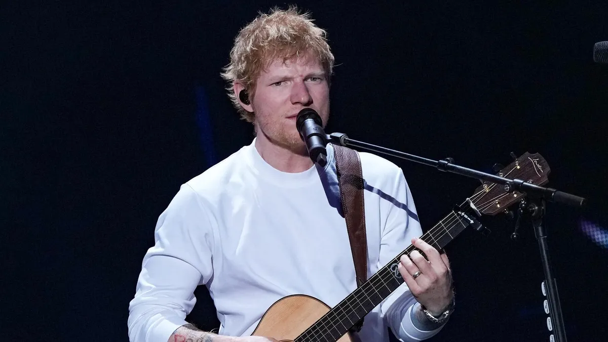 Ed Sheeran performing on stage with a guitar.