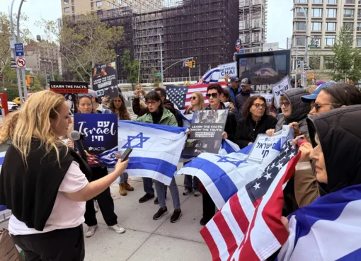 Protesters outside a film festival premiere, showing footage on a screen.