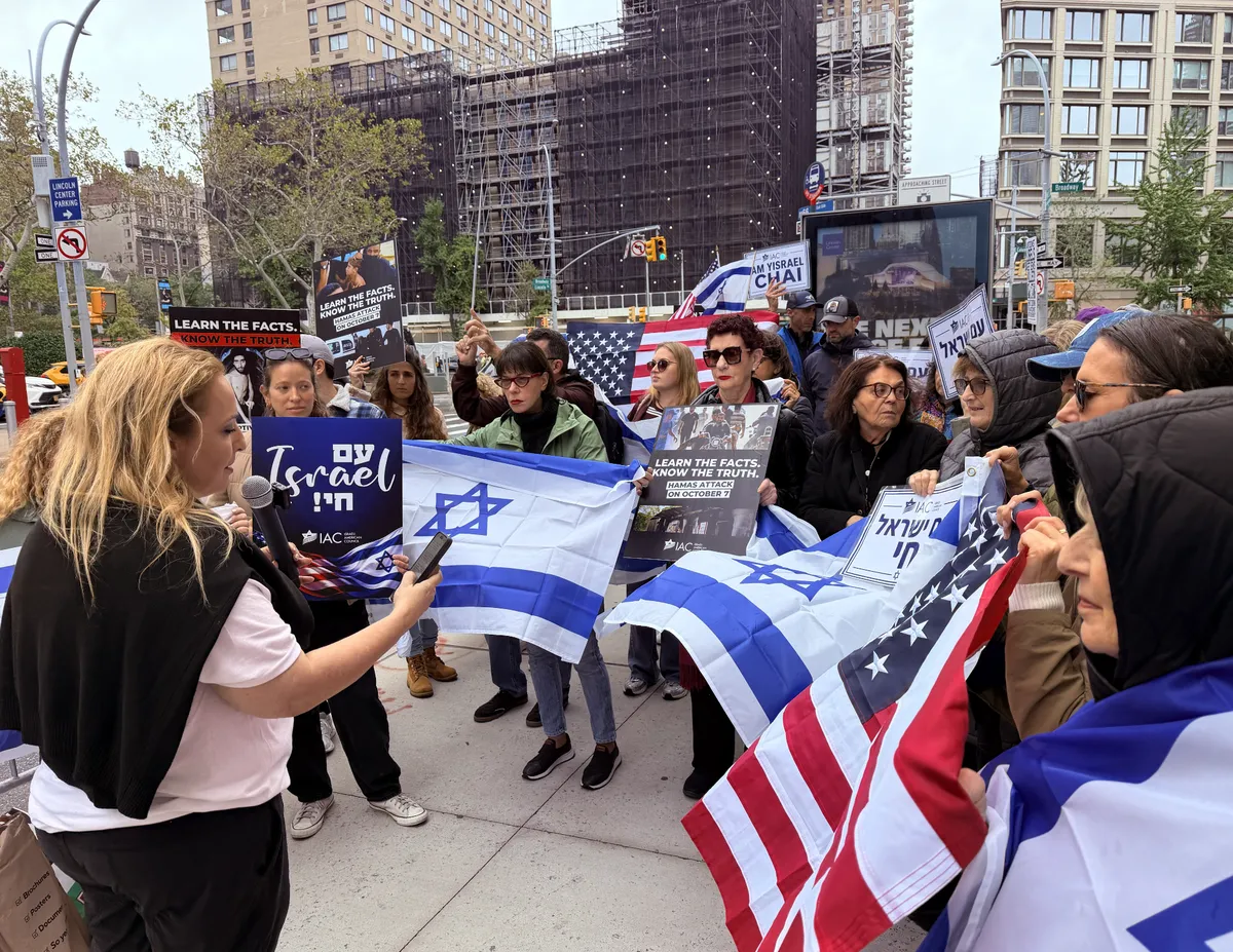 Protesters outside a film festival premiere, showing footage on a screen.
