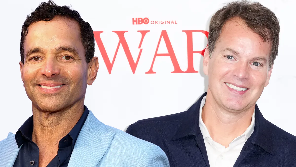 Two media executives standing on a red carpet.