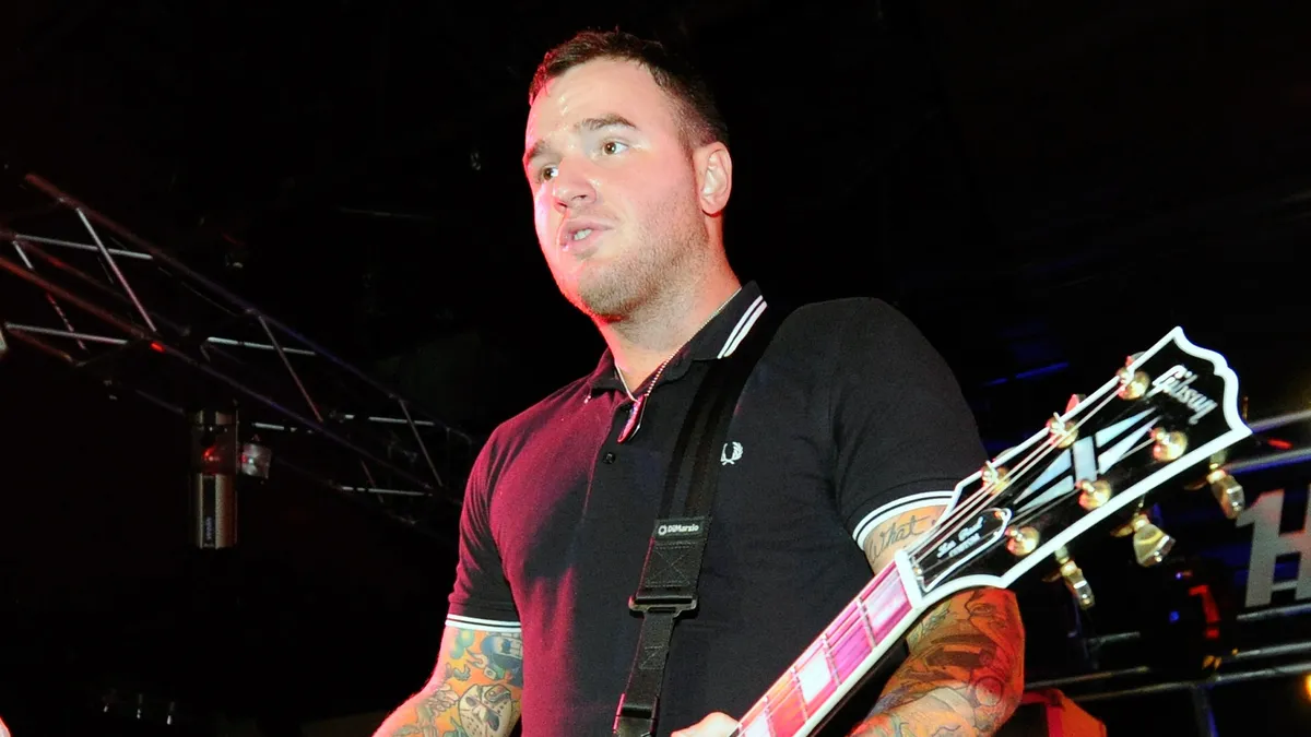 Chad Gilbert, guitarist for New Found Glory, smiling and playing his guitar on stage.