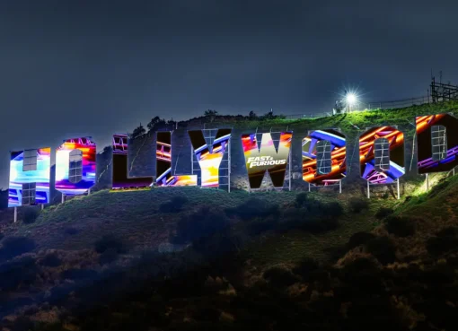 The Hollywood Sign illuminated with colorful Fast & Furious imagery.