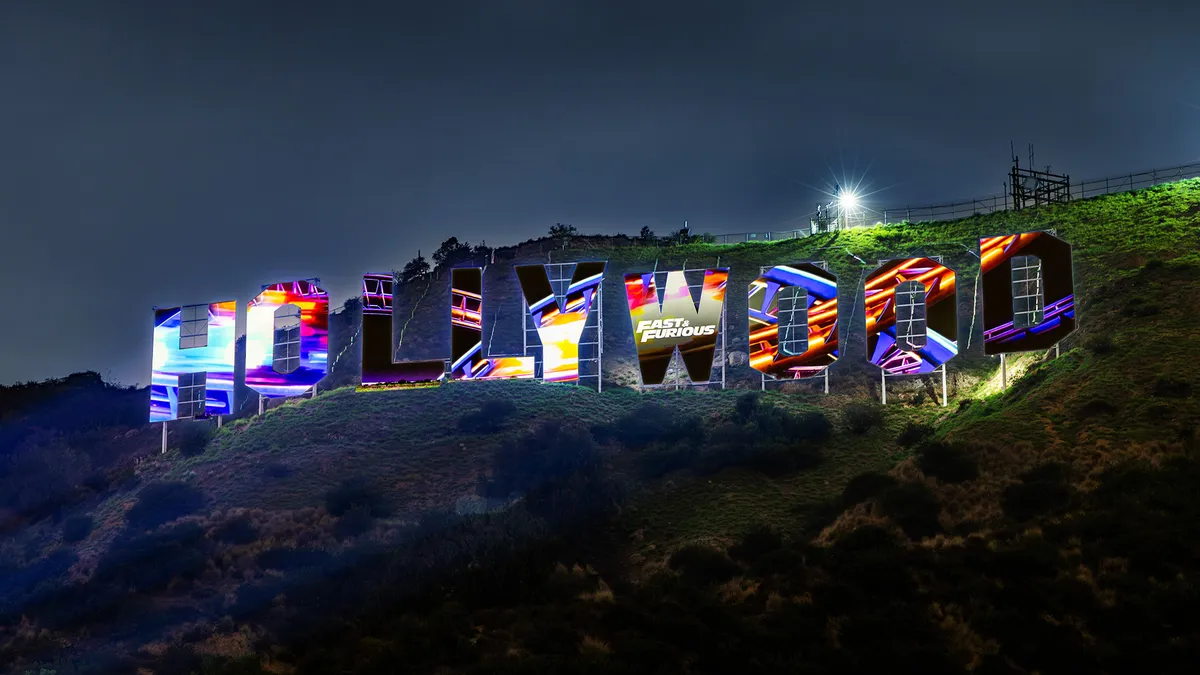 The Hollywood Sign illuminated with colorful Fast & Furious imagery.