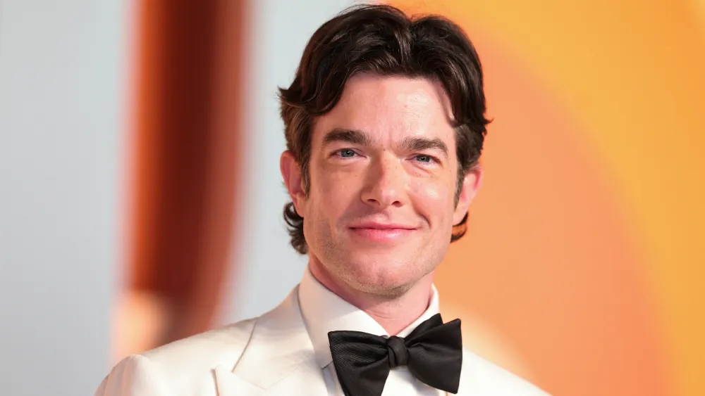 John Mulaney smiling on stage.