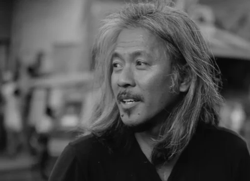 A black and white portrait of filmmaker Lav Diaz looking thoughtful.