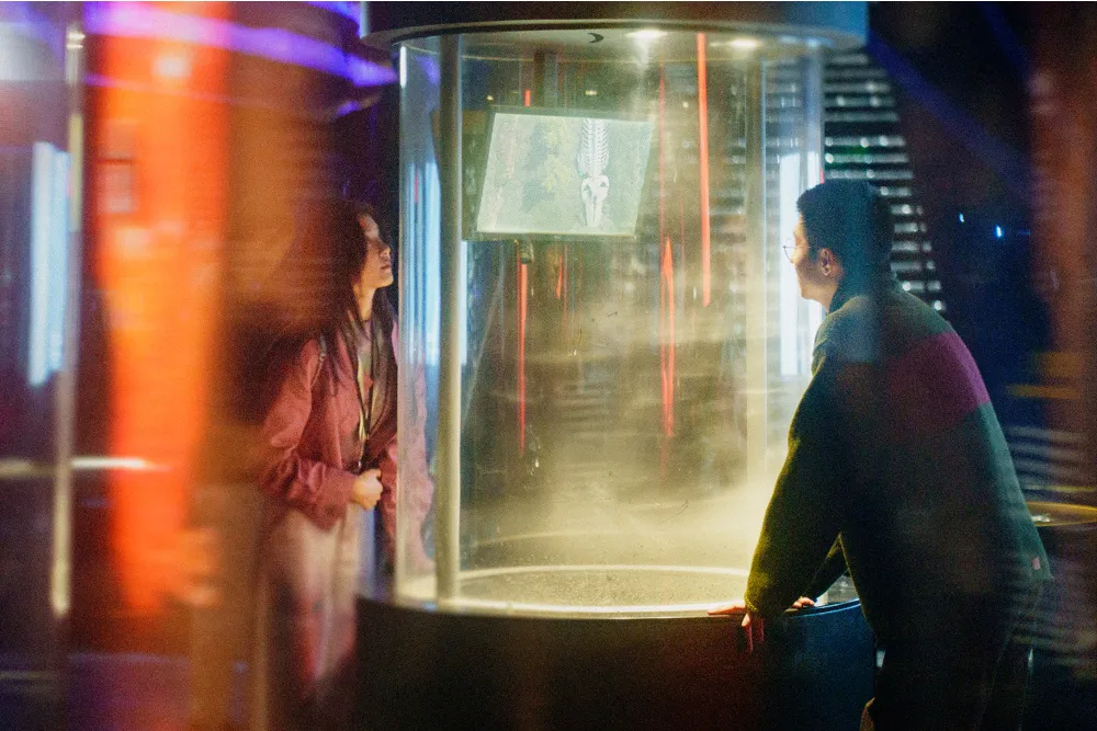 A still from 'Zoom In, Zoom Out' showing a contemplative young man, Shi, a game designer, looking into an empty space, possibly a room.