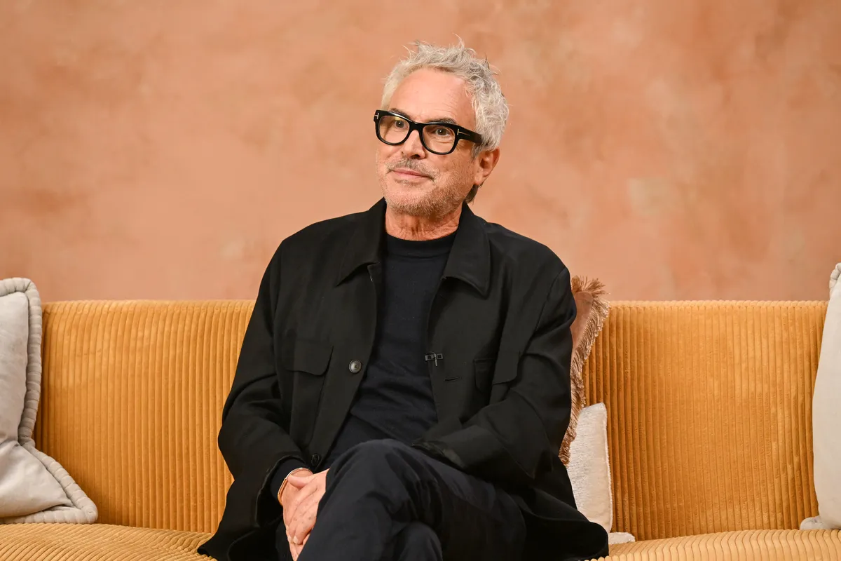 Alfonso Cuarón with film reels, surrounded by a vibrant film festival crowd.