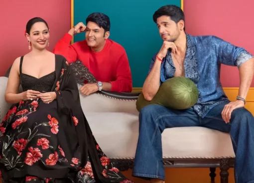 Kapil Sharma laughing with Sidharth Malhotra and Tamannaah Bhatia on his show stage, with bright lights.