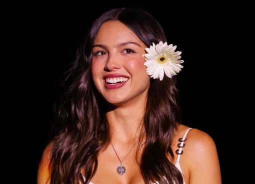 Olivia Rodrigo smiling on stage at a festival.