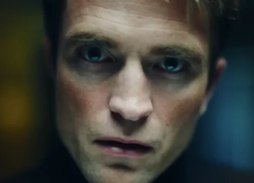 Robert Pattinson looking intense in a dimly lit scene.