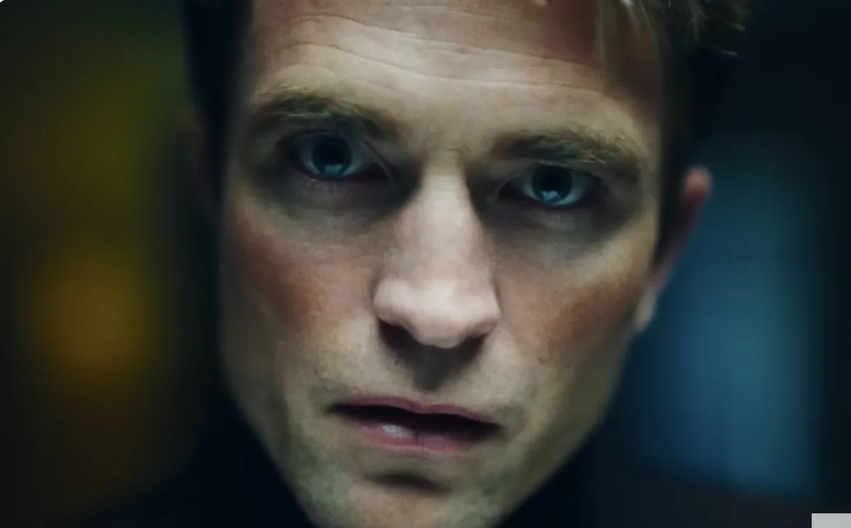 Robert Pattinson looking intense in a dimly lit scene.