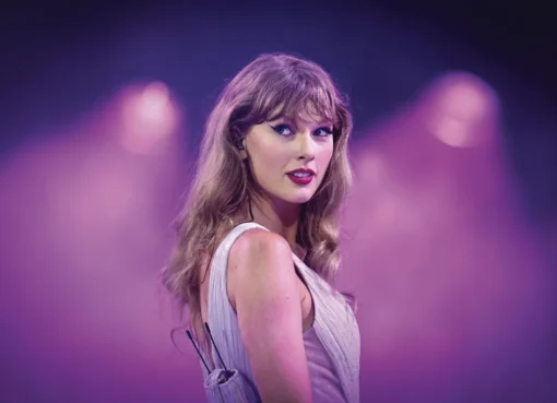 Taylor Swift performing on stage with a microphone, bathed in dramatic stage lighting.