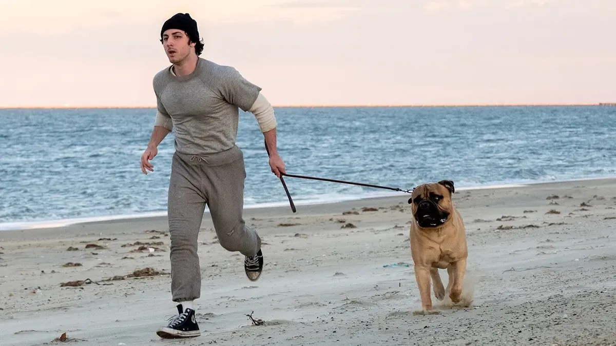 A cinematic shot of a young actor playing Sylvester Stallone on a 1970s movie set