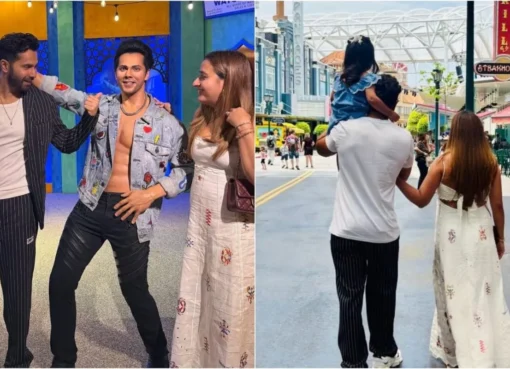 Varun Dhawan standing next to his wax figure while holding his daughter Lara.