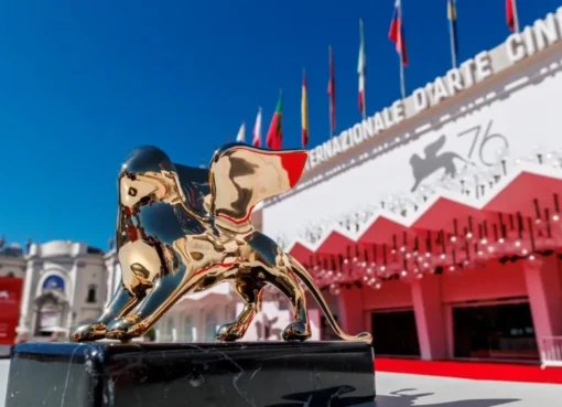 The iconic Golden Lion trophy glowing under spotlights at the Venice Film Festival.