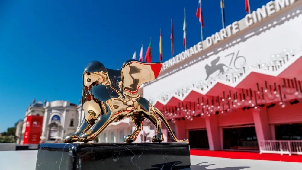 The iconic Golden Lion trophy glowing under spotlights at the Venice Film Festival.