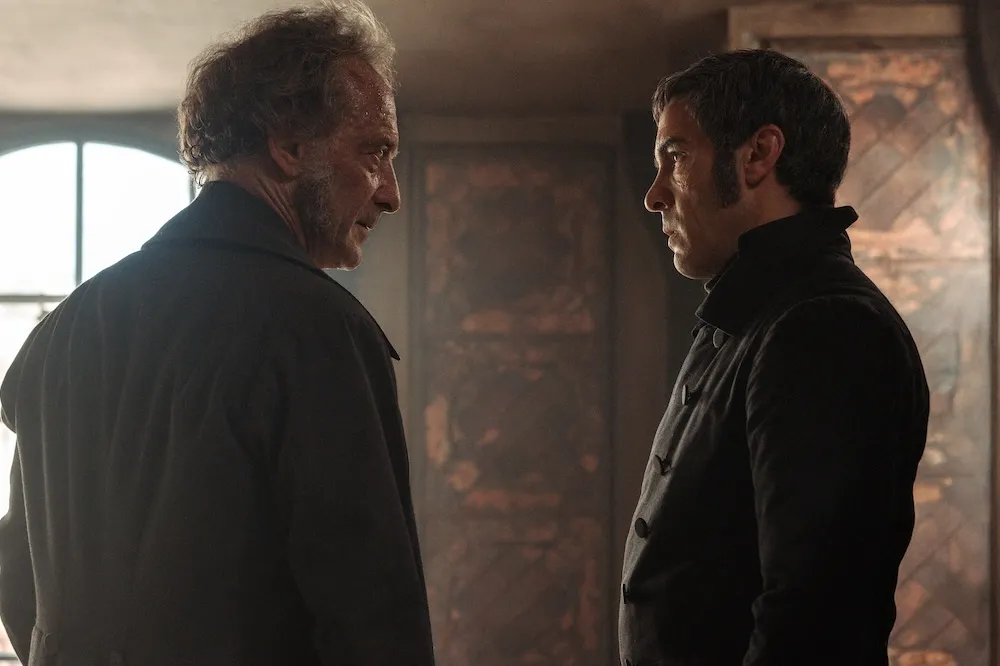 A dramatic still from the new French-language 'Les Misérables' film, featuring actors in historical costumes looking serious.