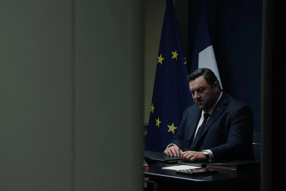 French President Paul Archambault, played by Denis Menochet, looking serious in a tense scene from the movie 'Jupiter'.