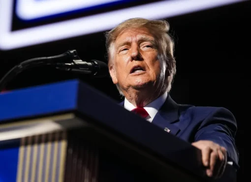 A stern-looking Donald Trump speaks at a podium in the White House.