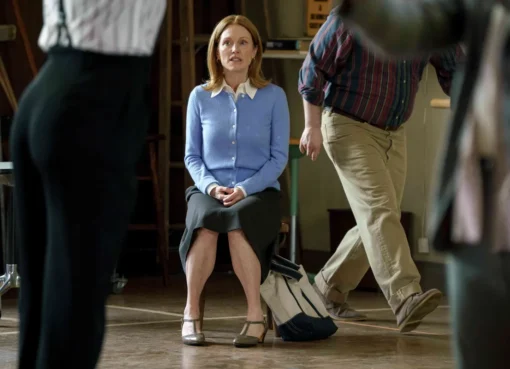 Julianne Moore on a film set, wearing a toolbelt and holding an unlit cigarette.