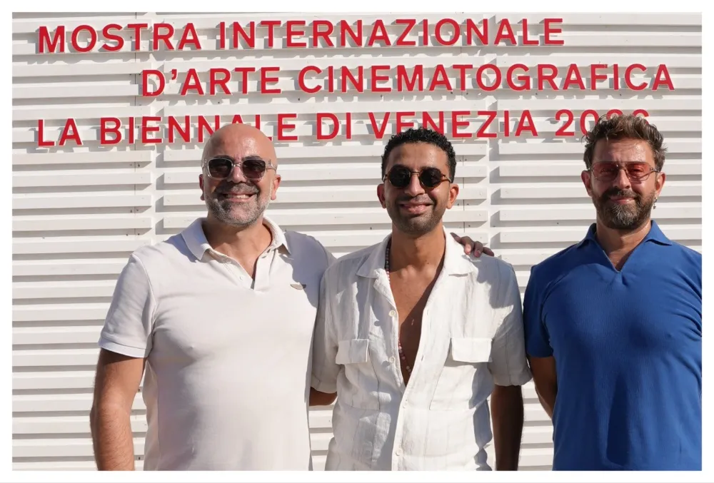 A photo of people shaking hands at the Venice Film Festival, symbolizing a new content partnership.