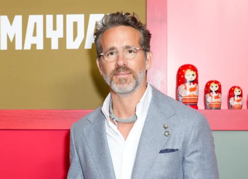 Ryan Reynolds smiling brightly, possibly at an event or premiere.