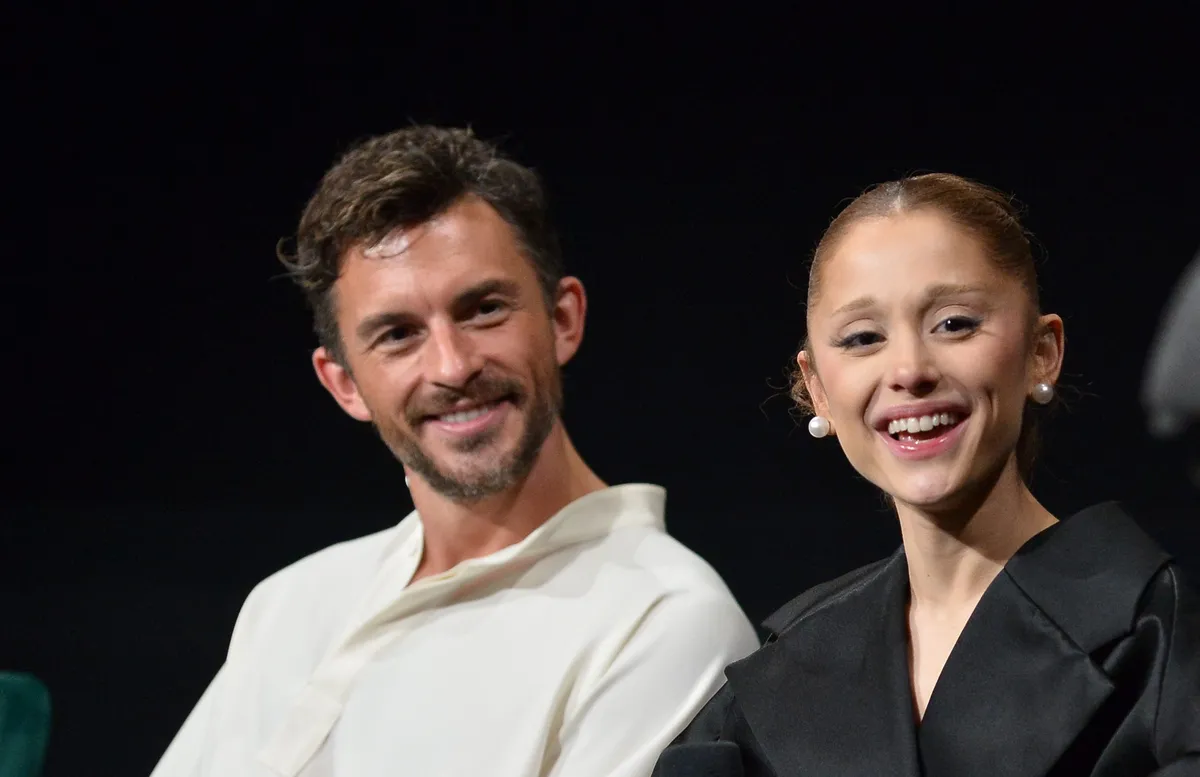 Ariana Grande and Jonathan Bailey smiling and looking surprised.