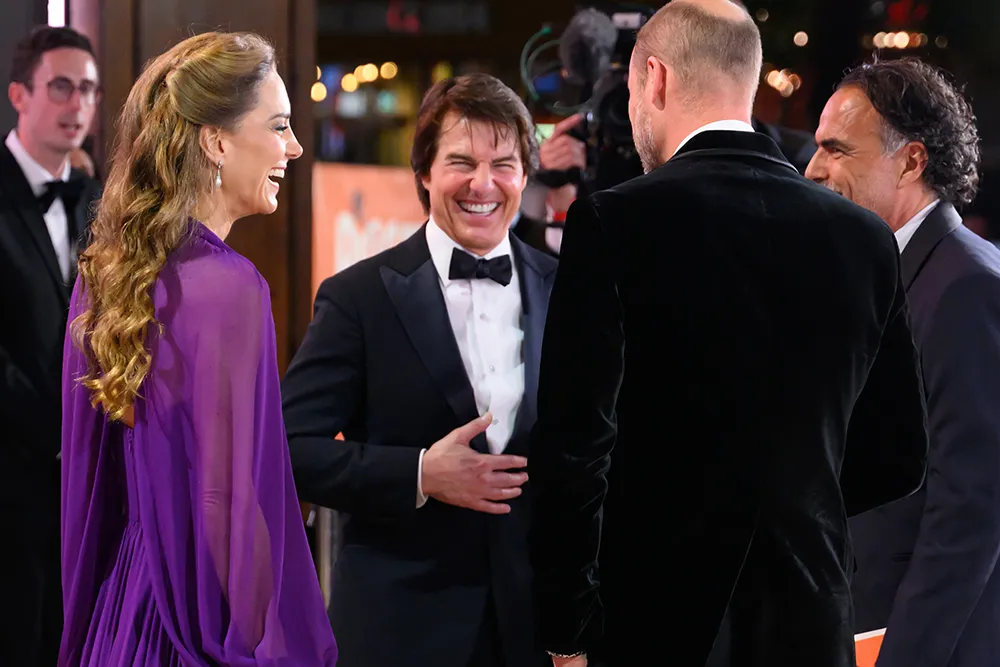 Tom Cruise smiling with Prince William and Princess Kate Middleton on a red carpet at the 'Digger' movie premiere.