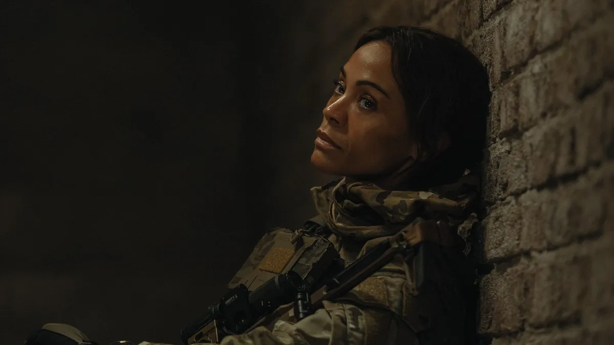 Zoe Saldaña smiling in a casual setting.