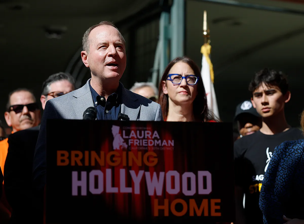 A group of people, including Sen. Adam Schiff, speaking at a podium with microphones, suggesting a political campaign or announcement related to film incentives.