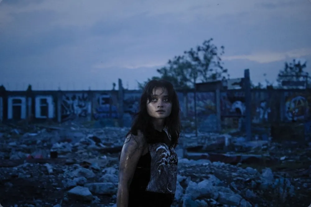A young woman with a folk-punk style, possibly in a gritty urban setting, ready to fight for her home.