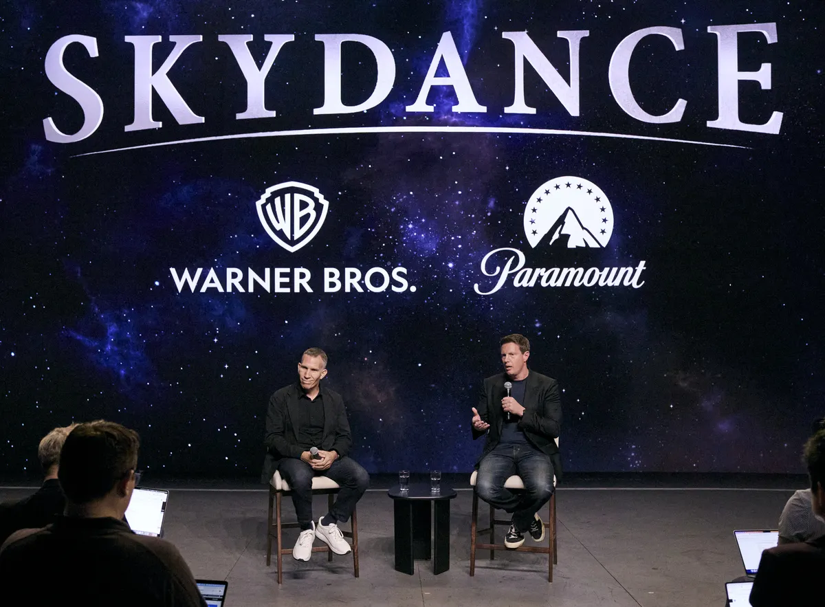 David Ellison and Ynon Kreiz at a press conference, both wearing jeans.