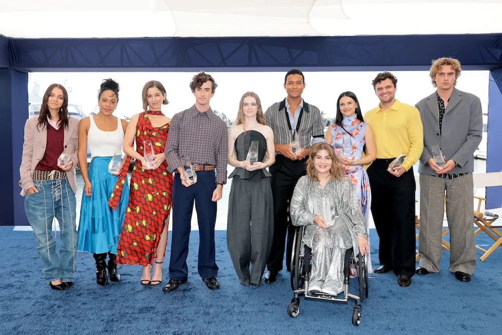 Group of diverse rising actors on a brightly lit stage at a film festival, smiling and talking.