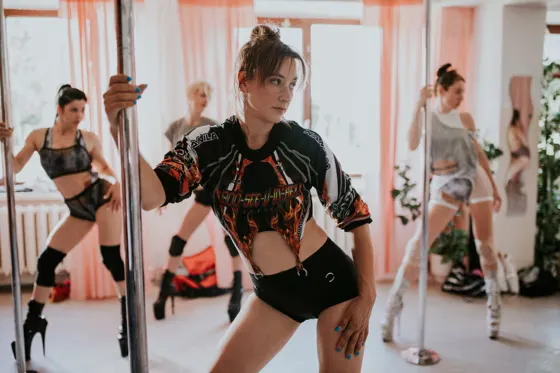A woman mid-pose on a pole, demonstrating strength and grace.