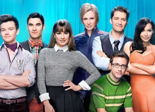 Photo of the Glee cast singing and dancing on stage in bright, colorful outfits with microphones.