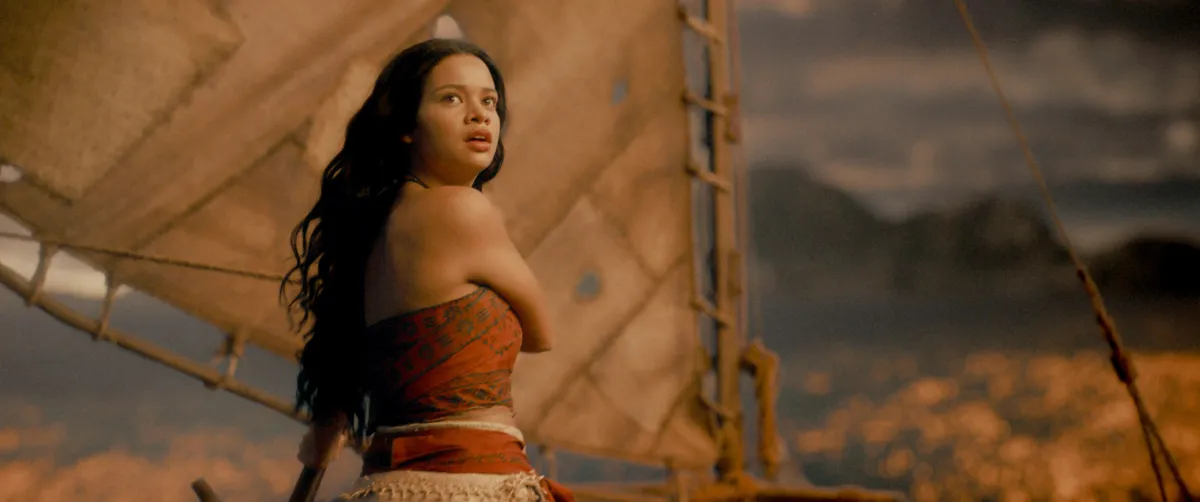 Catherine Laga'aia as Moana in the live-action remake, with a colorful tropical background.