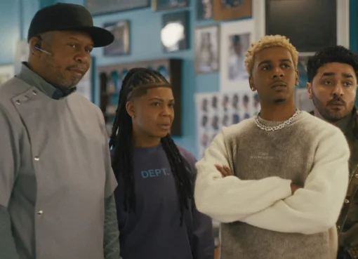 Jermaine Fowler looking slightly overwhelmed but determined in a lively barbershop scene.