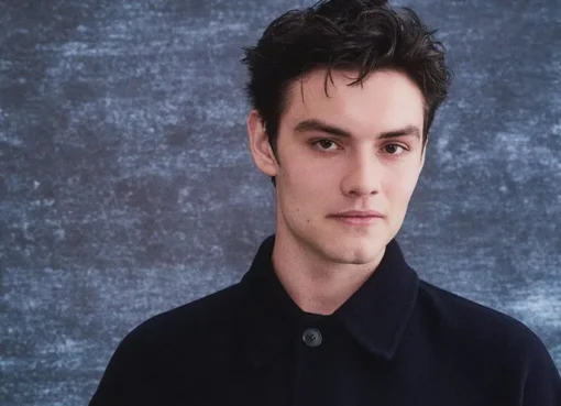 Louis Partridge smiling at the camera.