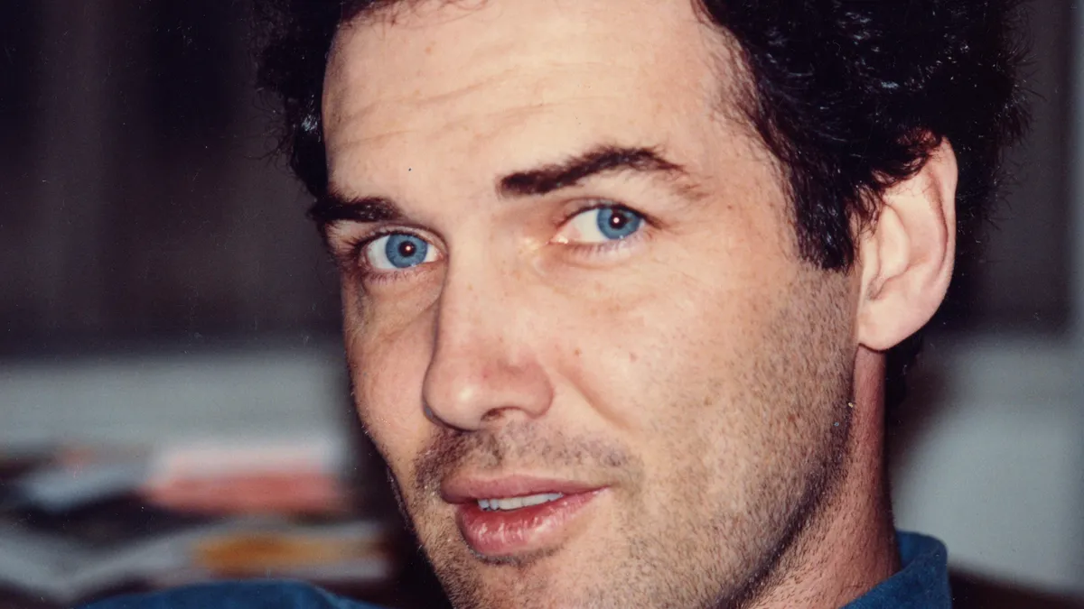 A close-up photo of Norm MacDonald with a thoughtful and slightly mischievous expression.