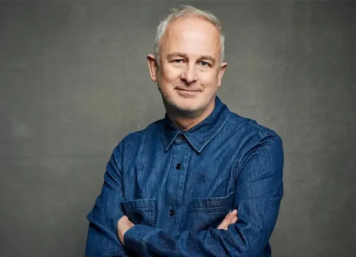 Director Dominic Cooke smiling subtly.
