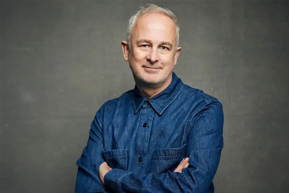 Director Dominic Cooke smiling subtly.