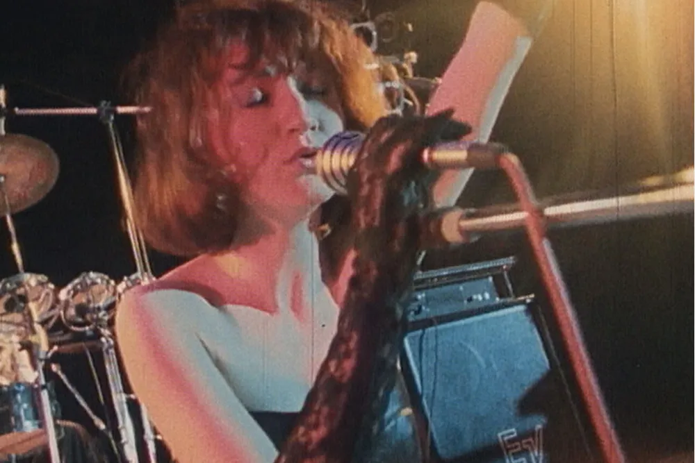 Bára Basiková on stage, singing with passion into a microphone.
