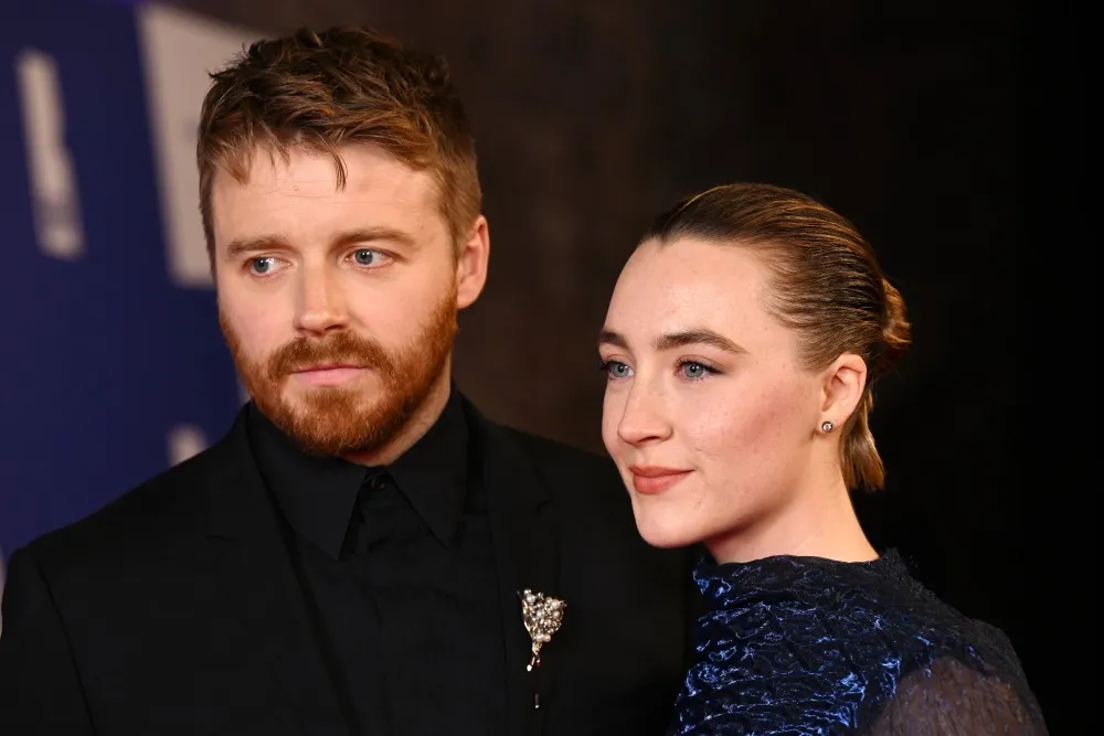 Saoirse Ronan smiling warmly, with a subtle backdrop that suggests her husband, Jack Lowden.