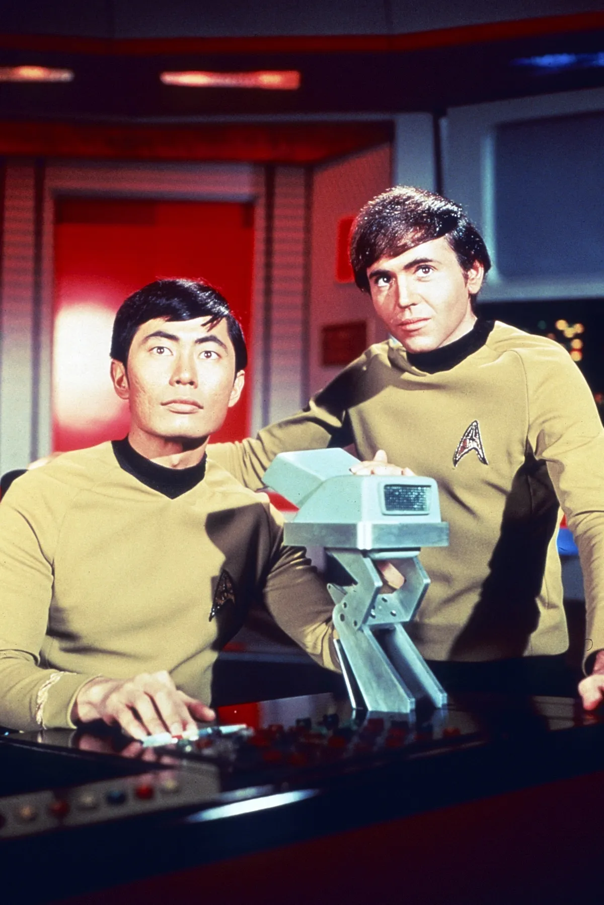 Walter Koenig as Chekov and George Takei as Sulu smiling on the bridge of the Starship Enterprise.