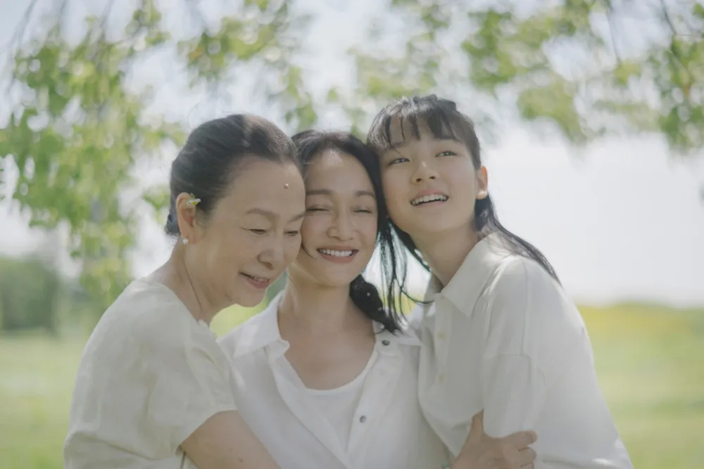 Three women of different generations sitting together, looking pensive or sad, representing family grief.